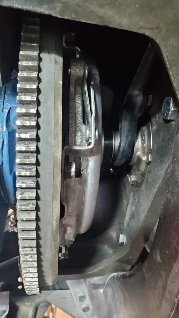 View from below: New clutch bolted to the engine flywheel. You can see the black fork engages the throwout bearing and the input shaft/bearing retainer peeking through on the right. 
When you press the clutch pedal, the fork pushes the bearing forward which pushes against clutch diaphragm fingers releasing pressure against the disc and flywheel.