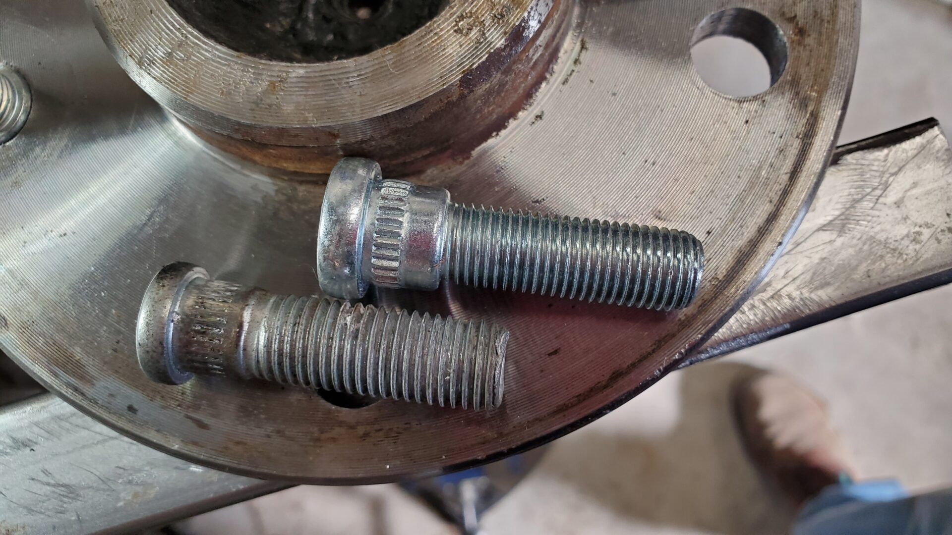 Metric wheel stud (bottom) vs 7/16" (top). Notice the much larger knurled shank.