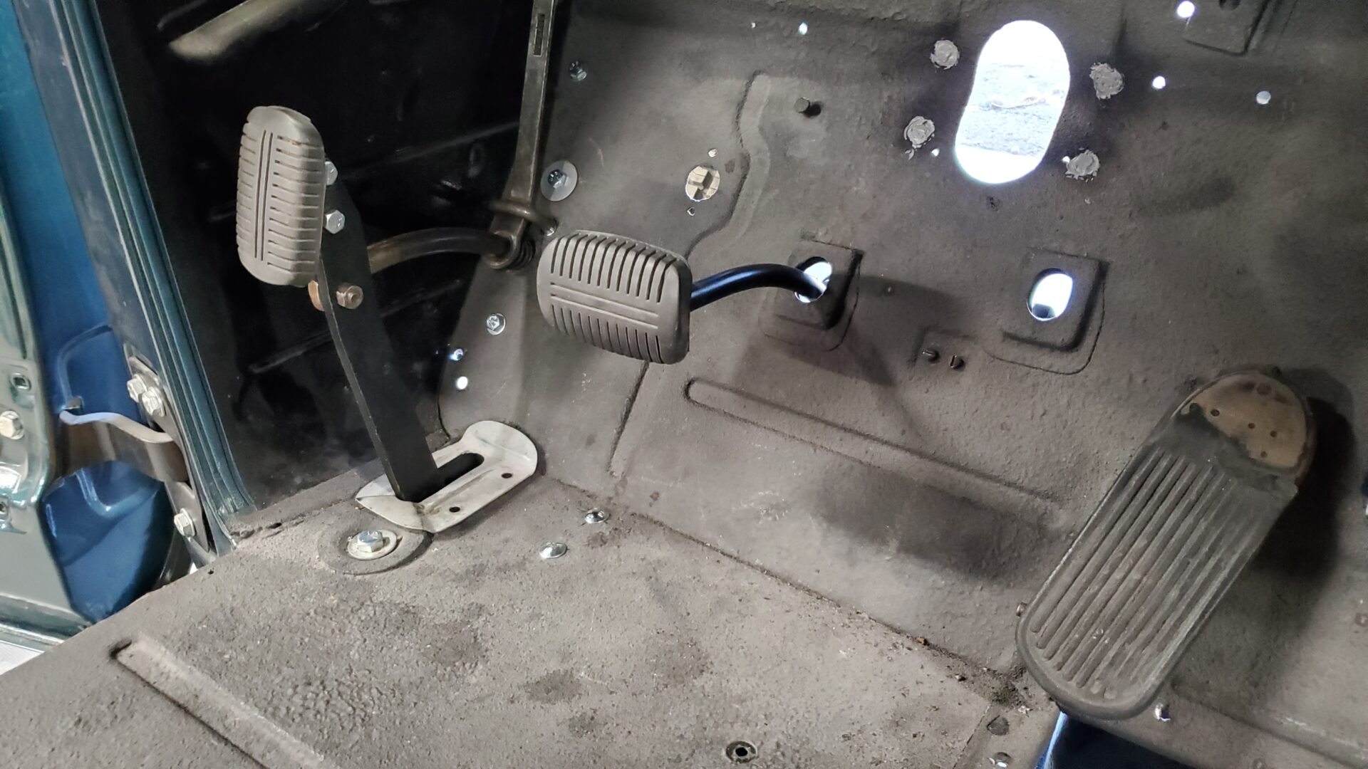 You can see the assembled parking brake (left) and the clutch pedal coming out of the floor. The brake pedal will come through the hole to the right of that. Notice how the hole is oddly offset vertically. The pedal also sticks through much farther than the clutch.